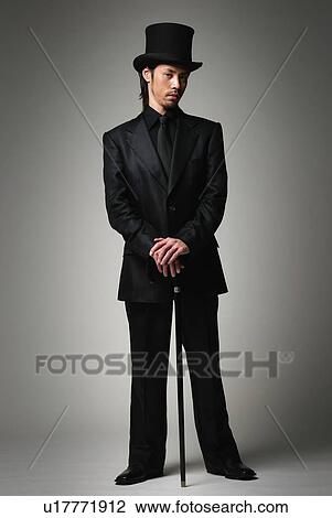 Stock Image - Young Man in Black with Hat and Stick, Front View. Fotosearch
