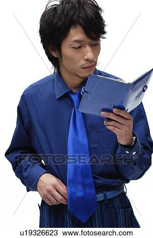Stock Image - Young Man in Blue Checking the Schedule Book, Front View. Fotosearch