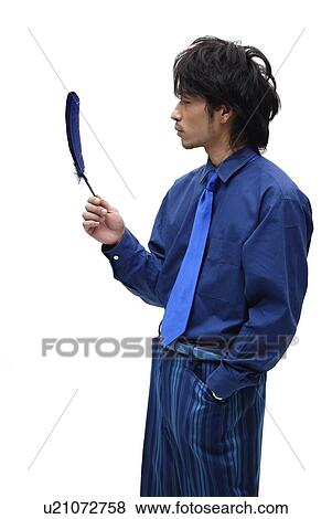 Stock Photo - Young Man in Blue Holding a Feather, Side View. Fotosearch