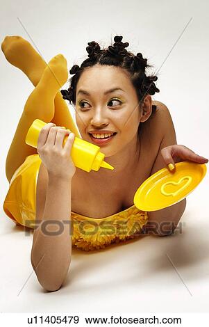 Stock Photo - Young Woman Holding Mustard, High Angle View. Fotosearch