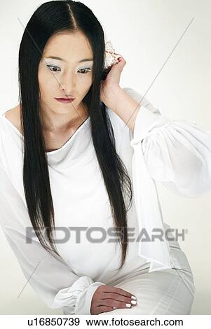 Stock Photo - Young Woman in White Listening, High Angle View. Fotosearch