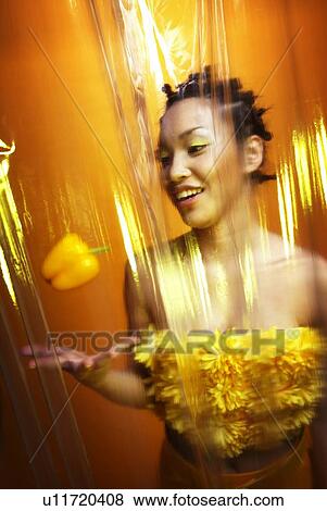 Stock Photo - Young Woman Playing with Yellow Paprika, Front View. Fotosearch