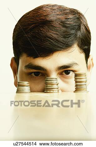 Picture - Close-up of a businessman behind stack of coins. Fotosearch