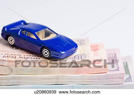 Stock Photo - Close-up of a toy car on a stack of Indian banknotes of different denominations. Fotosearch