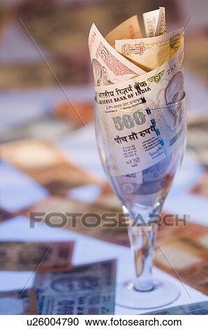 Stock Image - Close-up of Indian banknotes in a stem glass. Fotosearch