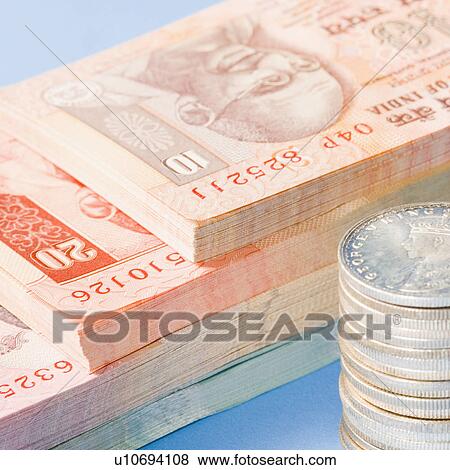 Stock Photo - Close-up of Indian banknotes with a stack of Indian silver coins. Fotosearch