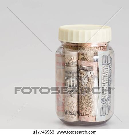 Stock Image - Close-up of rolled up bundles of Indian banknotes of different denominations in a jar. Fotosearch