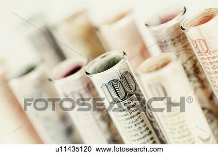 Stock Image - Close-up of test tubes wrapped with Indian banknotes of different denominations. Fotosearch