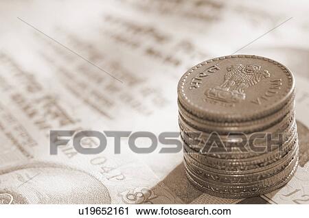 Stock Image - High angle view of a stack of Indian coins on Indian banknotes. Fotosearch