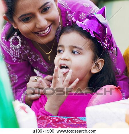 Close-up of a girl licking icing of a birthday cake and her mother smiling behind her View Large Photo Image Stock Image - Close-up of a girl licking icing of a birthday cake and her mother smiling behind her. Fotosearch