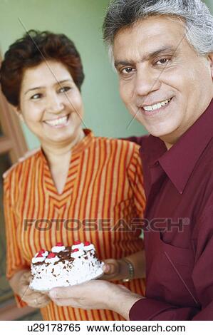 Close-up of a mature couple holding a birthday cake View Large Photo Image Stock Photography - Close-up of a mature couple holding a birthday cake. Fotosearch