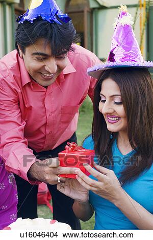 Picture - Close-up of a young man giving a birthday gift to a young woman. Fotosearch