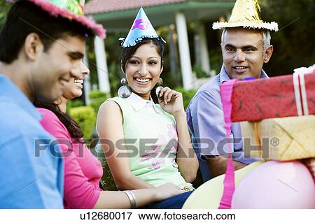 Stock Photo - Four people celebrating a party and smiling. Fotosearch