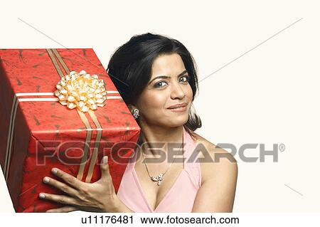 Stock Image - Portrait of a young woman holding a gift. Fotosearch