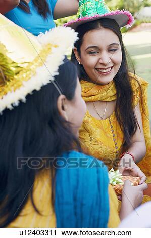Stock Image - Rear view of a mid adult woman giving a birthday present to a young woman. Fotosearch