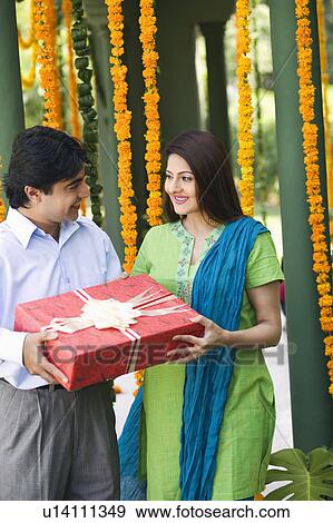 Young couple holding a gift View Large Photo Image Stock Photo - Young couple holding a gift. Fotosearch
