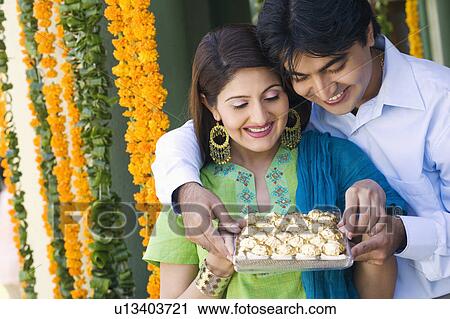 Stock Image - Young couple holding a tray of cookies. Fotosearch