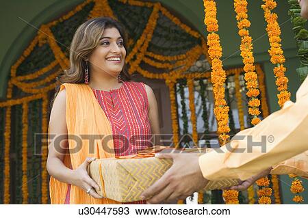 Young woman receiving a gift from a man View Large Photo Image Stock Image - Young woman receiving a gift from a man. Fotosearch