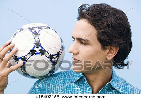 Stock Photo - Close-up of a young man holding a soccer ball on his shoulder. Fotosearch