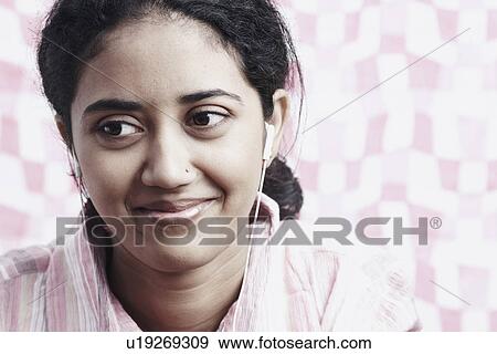 Stock Photo - Close-up of a young woman listening to music. Fotosearch