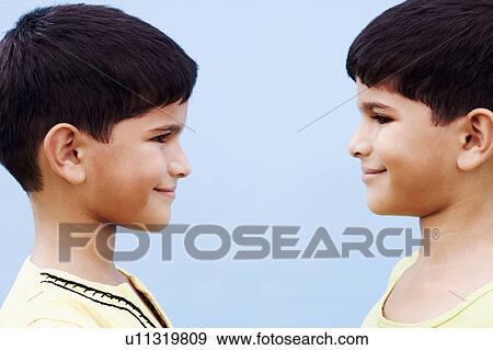 Side profile of twin brothers looking at each other View Large Photo Image Stock Photo - Side profile of twin brothers looking at each other. Fotosearch