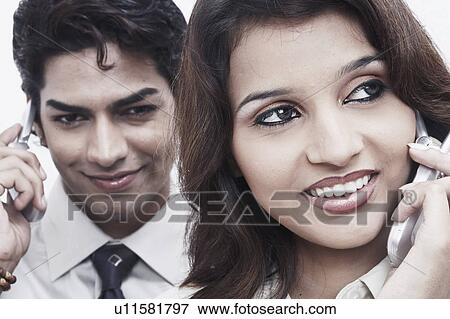 Stock Photo - Close-up of a businessman and a businesswoman talking on mobile phones. Fotosearch