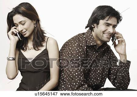 Stock Photo - Close-up of a young couple talking on mobile phones. Fotosearch