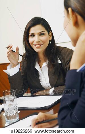 Stock Photograph - Close-up of two businesswomen sitting in a meeting. Fotosearch