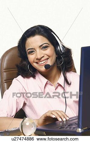Portrait of a businesswoman wearing a headset and smiling in front of a laptop View Large Photo Image Stock Photograph - Portrait of a businesswoman wearing a headset and smiling in front of a laptop. Fotosearch