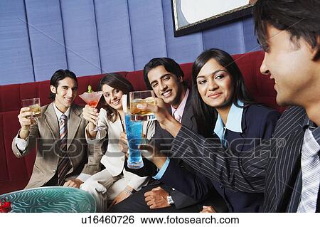 Two businesswomen and three businessmen sitting on a couch and toasting with glasses View Large Photo Image Stock Photograph - Two businesswomen and three businessmen sitting on a couch and toasting with glasses. Fotosearch