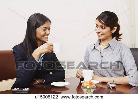 Two businesswomen sitting in an office and drinking tea View Large Photo Image Stock Image - Two businesswomen sitting in an office and drinking tea. Fotosearch