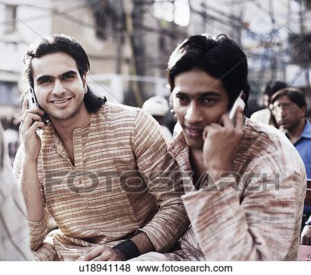 Two young men sitting in a rickshaw and talking on mobile phones View Large Photo Image Stock Photo - Two young men sitting in a rickshaw and talking on mobile phones. Fotosearch