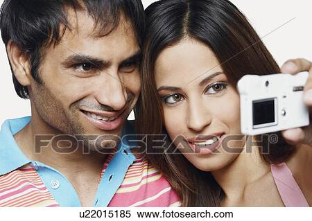 Close-up of a young couple taking a photograph of themselves View Large Photo Image Stock Photography - Close-up of a young couple taking a photograph of themselves. Fotosearch