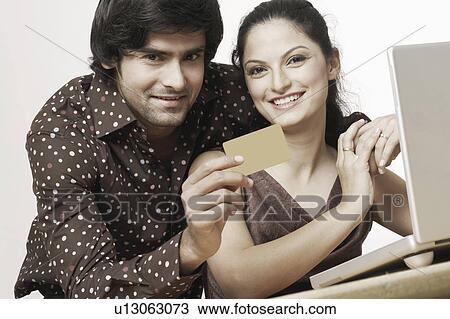 Portrait of a young couple sitting in front of a laptop with a credit card View Large Photo Image Stock Image - Portrait of a young couple sitting in front of a laptop with a credit card. Fotosearch