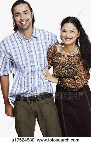 Portrait of a young couple standing with their arms around each other and smiling View Large Photo Image Stock Image - Portrait of a young couple standing with their arms around each other and smiling. Fotosearch