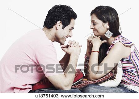 Stock Image - Side profile of a young couple looking at each other and smiling. Fotosearch