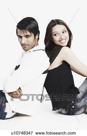 Stock Photo - Side profile of a young couple sitting back to back. Fotosearch