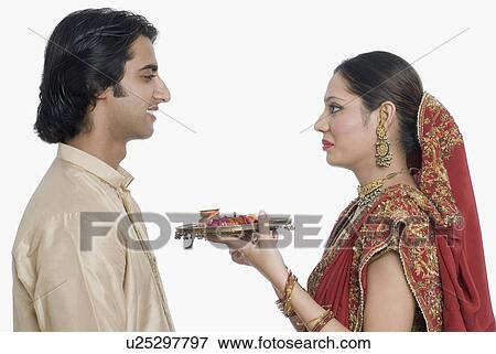 Side profile of a young woman holding a plate of traditional offerings in front of her husband View Large Photo Image Stock Photo - Side profile of a young woman holding a plate of traditional offerings in front of her husband. Fotosearch