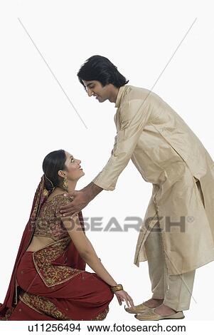 Side profile of a young woman touching feet of her husband on a traditional festival View Large Photo Image Picture - Side profile of a young woman touching feet of her husband on a traditional festival. Fotosearch