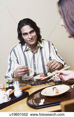 Close-up of a young couple sitting at a dining table and looking at each other View Large Photo Image Stock Image - Close-up of a young couple sitting at a dining table and looking at each other. Fotosearch