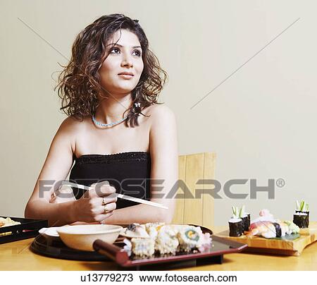 Stock Image - Close-up of a young woman sitting at the dining table. Fotosearch