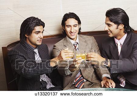 Stock Photo - Close-up of three businessmen toasting with glasses of whiskey. Fotosearch