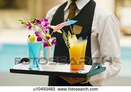 Stock Image - Mid section view of a waiter holding a tray of drinks. Fotosearch