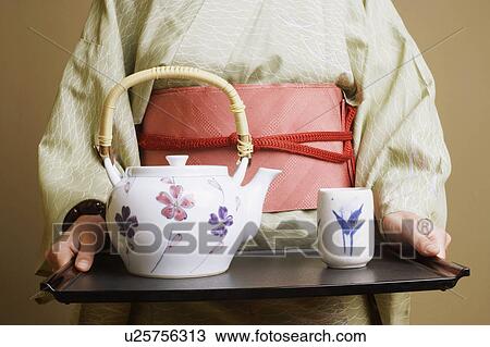 Mid section view of a young woman wearing a kimono and holding a tray View Large Photo Image Stock Image - Mid section view of a young woman wearing a kimono and holding a tray. Fotosearch