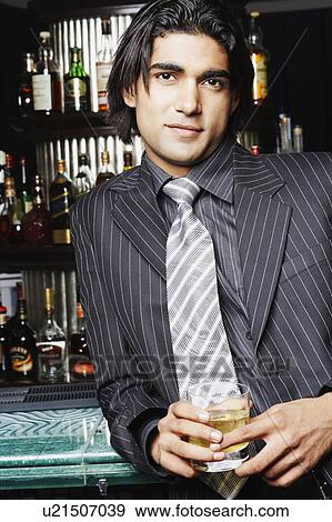 Portrait of a businessman holding a glass of whiskey at a bar counter View Large Photo Image Stock Photo - Portrait of a businessman holding a glass of whiskey at a bar counter. Fotosearch