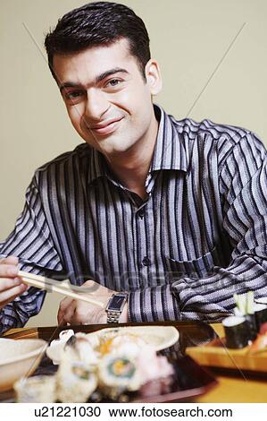 Portrait of a young man sitting at the dining table and smirking View Large Photo Image Stock Image - Portrait of a young man sitting at the dining table and smirking. Fotosearch