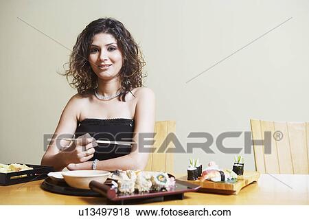 Portrait of a young woman sitting at the dining table and smiling View Large Photo Image Stock Photo - Portrait of a young woman sitting at the dining table and smiling. Fotosearch