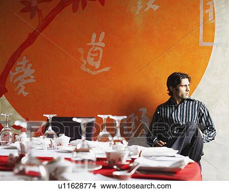 Young man sitting in a restaurant View Large Photo Image Picture - Young man sitting in a restaurant. Fotosearch