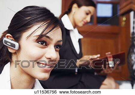 Stock Photograph - Close-up of a businesswoman wearing a hands free device. Fotosearch