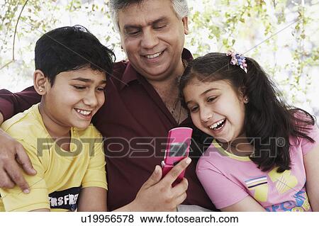 Close-up of a mature man and his grandchildren looking at a mobile phone View Large Photo Image Stock Photo - Close-up of a mature man and his grandchildren looking at a mobile phone. Fotosearch